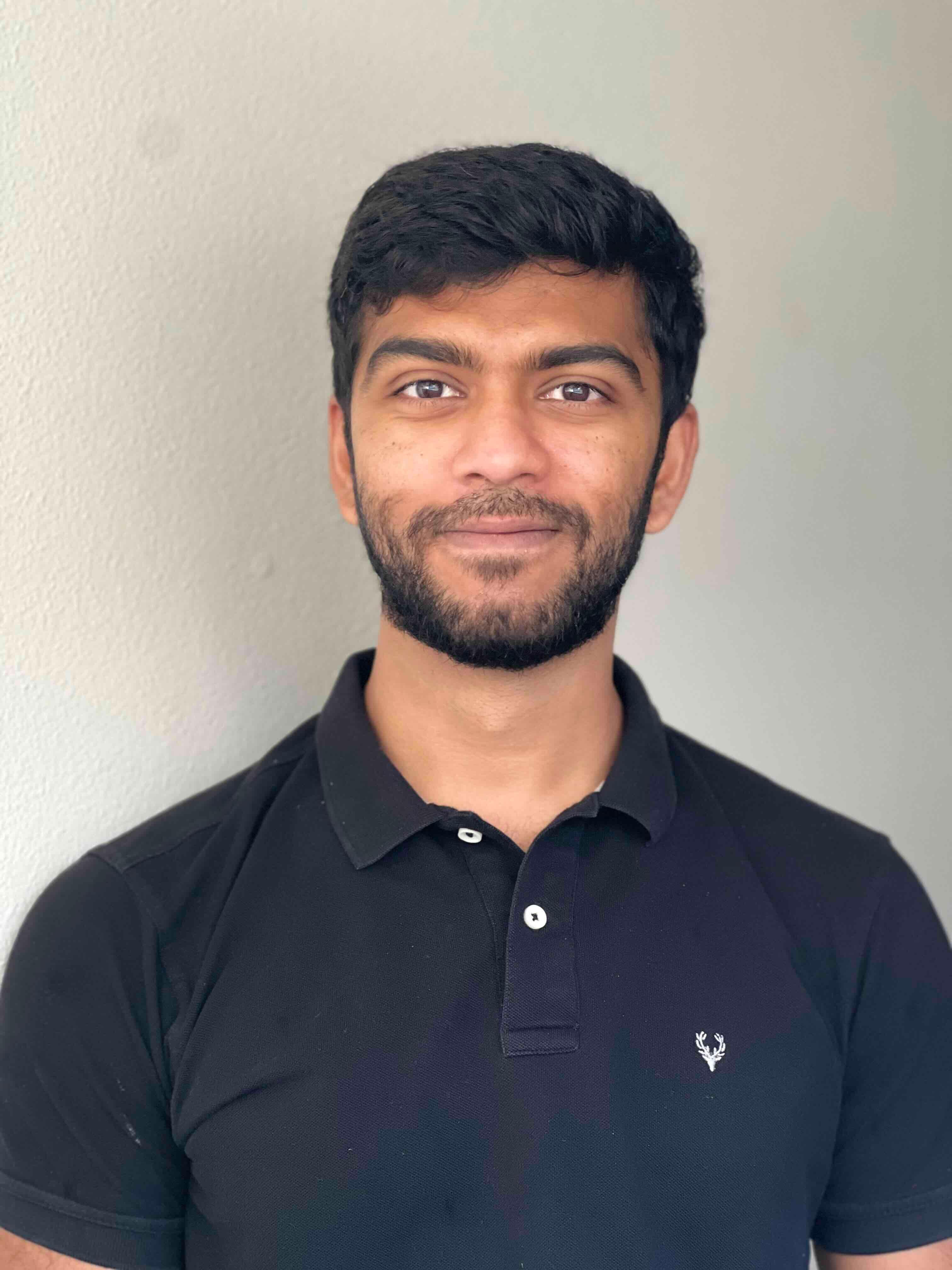 Image of Ayush Srivastava, a brown man smiling with black hair. (Beard optional